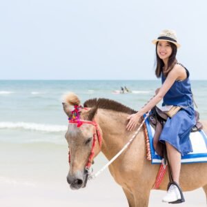 Woman riding horse on sand beach